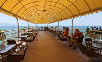 a restaurant with a large terrace , where people are sitting at tables under a yellow canopy at Hotel New York