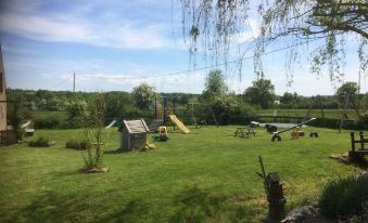a grassy field with a picnic table and chairs , as well as a swing set at Le Petit Moulin