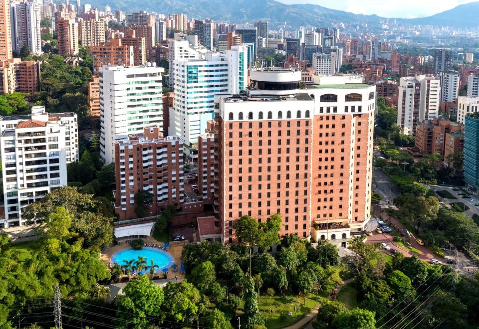 a large hotel surrounded by a cityscape , with a pool visible in the center of the building at Dann Carlton Medellin Hotel
