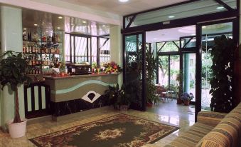 a hotel lobby with a bar and a couch , as well as potted plants and chairs at Hotel Hamilton