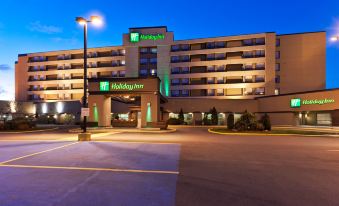 a large hotel building with a parking lot in front of it , illuminated at night at Holiday Inn Laval - Montreal