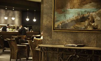 a man sitting at a desk in a dimly lit room , surrounded by chairs and a painting on the wall at Hotel Cabo de Hornos