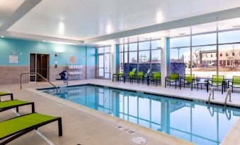 an indoor swimming pool with a large window , surrounded by lounge chairs and umbrellas , in a modern building at SpringHill Suites Columbia