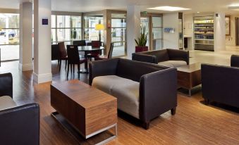 a modern lounge area with wooden floors , leather couches , and tables , surrounded by windows and large windows at Holiday Inn Express Milton Keynes