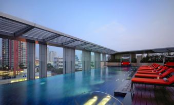 There is a rooftop swimming pool with large windows offering an outside view and blue water at Bangkok Marriott Hotel Sukhumvit