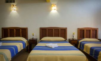 a hotel room with three beds , two of which are twin beds and one is a double bed at Hotel Restaurante Donaji