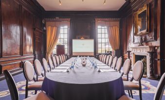 a long table with blue tablecloths and white chairs is set up in a room with wooden walls at Coombe Abbey Hotel