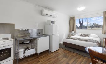 a clean and well - organized hotel room with a kitchenette , bed , and bathroom , all connected by a window at Broken Hill Tourist Park