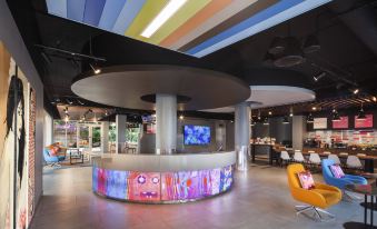 a modern restaurant with a curved bar and colorful lighting , creating an inviting atmosphere for dining at Aloft Miami Dadeland