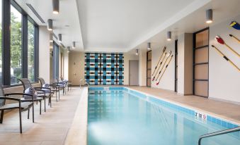 a large indoor swimming pool with a long , narrow shape and multiple lanes , surrounded by lounge chairs and a bookshelf at Residence Inn by Marriott Boston Watertown