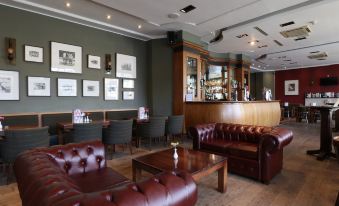 a cozy lounge area with leather couches , chairs , and a bar , creating a comfortable atmosphere for customers at Columba Hotel Inverness by Compass Hospitality