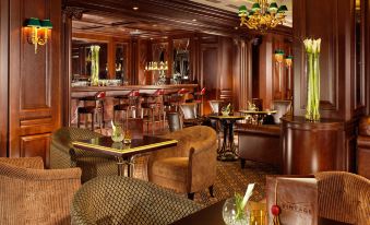 a well - decorated restaurant with wooden furniture , including couches and chairs , as well as a bar area at Fairmont Grand Hotel - Kyiv