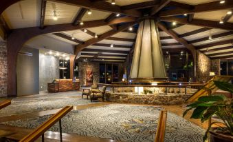 a spacious , well - lit lobby with a fireplace and wooden beams , lit by hanging lights , under a high ceiling at Lodge of Four Seasons Golf Resort, Marina & Spa