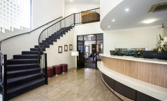 a modern office interior with a curved staircase , black staircase railing , and wooden desk area at Coral Cay Resort
