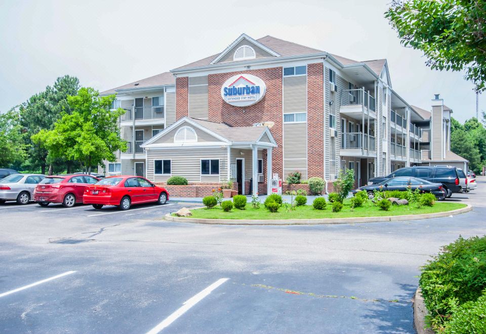 a large apartment building with a red car parked in front , surrounded by trees and grass at Siegel Select Bartlett