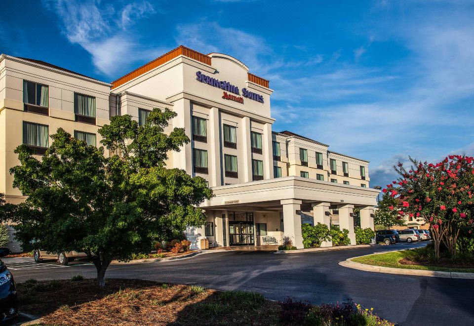 a holiday inn express hotel with its distinctive blue and white sign , surrounded by trees and bushes at SpringHill Suites Florence