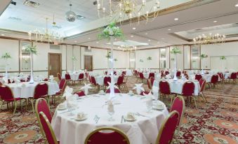 a large banquet hall with multiple round tables and chairs , all set for a formal event at Holiday Inn Staunton Conference Center