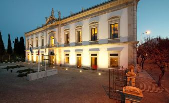 a large , white building with a balcony and red lanterns is illuminated at night in the evening at Pousada De Viseu