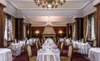 a formal dining room with white tablecloths and gold chairs , set for a dinner party at Doxford Hall Hotel and Spa