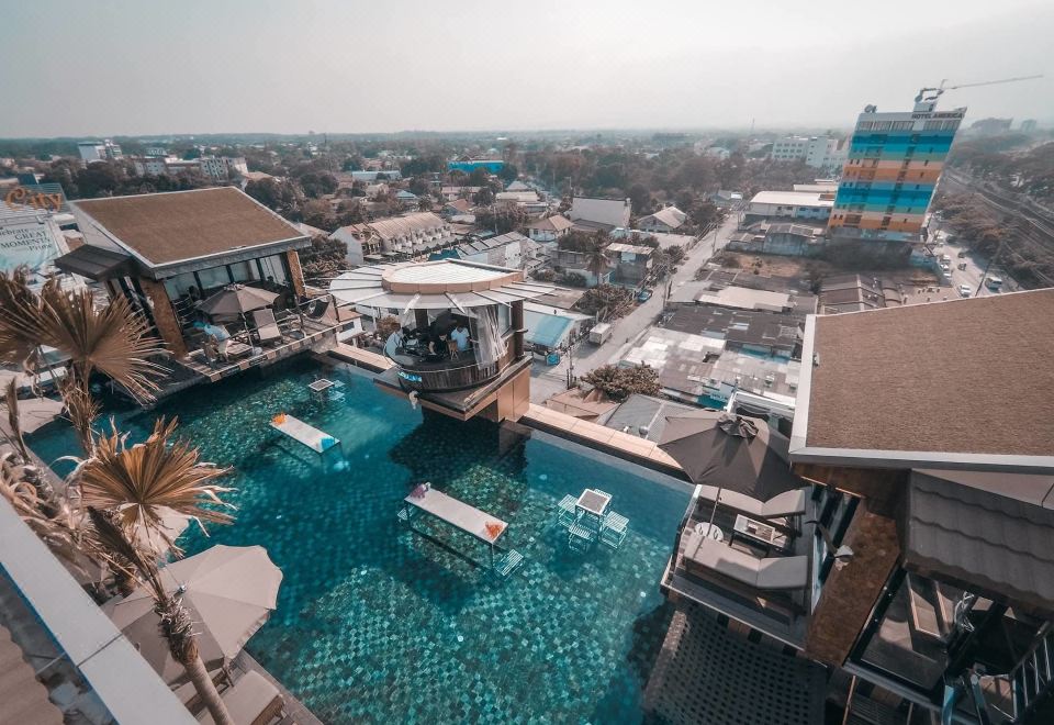 an aerial view of a rooftop pool surrounded by buildings , with a bar and lounge area nearby at ABC Hotel