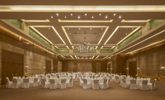 a large , well - lit banquet hall with multiple tables set up for a formal event , possibly a wedding reception at Marina Hotel