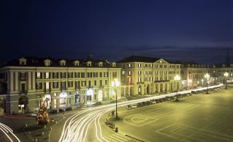 a nighttime scene of a city square with cars and buildings lit up , creating a vibrant atmosphere at Phi Hotel Principe