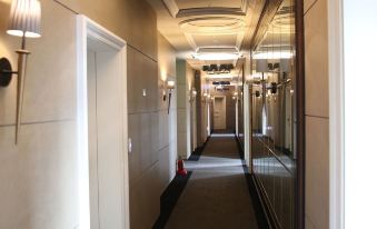 a long , dimly lit hallway with multiple doors and chandeliers , giving it a spacious and elegant feel at The Riverside Hotel