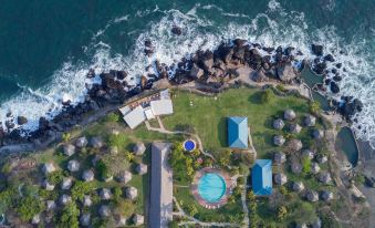 aerial view of a beach resort with a pool surrounded by rocks and the ocean at Atami Escape Resort