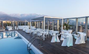 a rooftop pool area with tables , chairs , and a hot tub , surrounded by mountains in the background at Icon Hotel