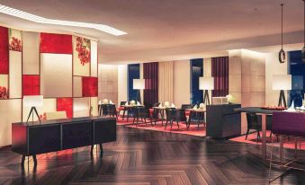 a modern lounge area with wooden floors , red and white walls , and a large table in the center at Mercure Hai Phong
