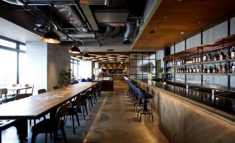 a large , well - lit restaurant with a long wooden bar and several dining tables , creating an inviting atmosphere for patrons at Kawasaki King Skyfront Tokyu Rei Hotel