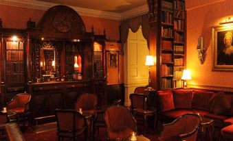 a cozy room with bookshelves , an antique clock , and red couches , creating a warm and inviting atmosphere at Lumley Castle Hotel