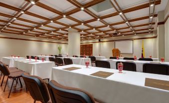 a conference room with rows of tables and chairs , a projector screen , and large windows at Lancaster House