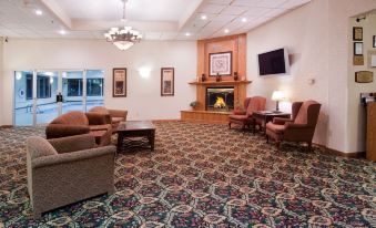 a large , well - lit living room with multiple couches and chairs arranged in front of a fireplace at Country Inn & Suites by Radisson, Sidney, NE