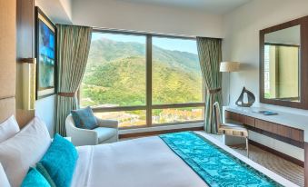 The bedroom is furnished and has large windows that overlook the city and mountains at Auberge Discovery Bay Hong Kong