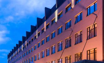 a large , modern hotel building with multiple windows and balconies , situated on a city street at dusk at Park Inn by Radisson Central Tallinn