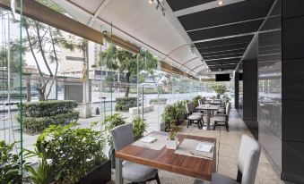 a modern restaurant with wooden tables and chairs , a potted plant on the patio , and large windows at Le Meridien Mexico City