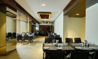 a large , well - lit dining room with multiple tables and chairs , creating an inviting atmosphere for guests at Hotel Apaar