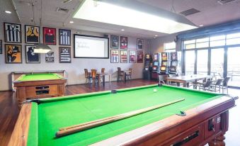 a pool table with a green felt surface and white border , set up in an indoor area with chairs and tables at Nightcap at Wanneroo Tavern