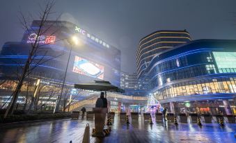 At night, a cityscape comes alive with illuminated buildings and people strolling through the streets at Holiday Inn Express Hangzhou East Station