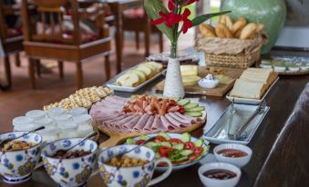 a table is set with a variety of food items , including sandwiches and drinks , on plates and bowls at Bai Dinh Garden Resort & Spa