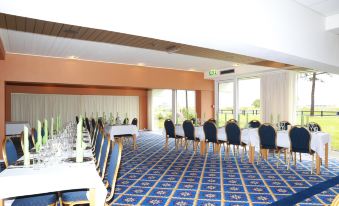 a large conference room with multiple tables and chairs arranged for a meeting or event at Hotel Marina