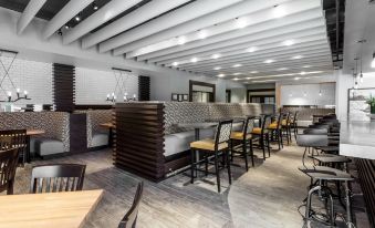 a modern restaurant with wooden tables and chairs , a bar area , and a large screen tv at Holiday Inn Chicago North-Evanston, an IHG Hotel