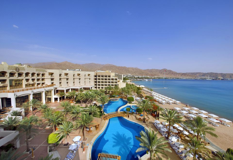 a large hotel complex with a large pool and palm trees in front of the ocean at InterContinental Hotels Aqaba (Resort Aqaba)