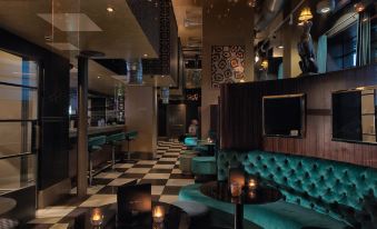 a modern bar with black and white checkered floor , blue couches , wooden tables , and candles at Malmaison Dundee