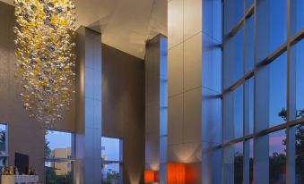 a modern hotel lobby with large windows , a bar area , and a chandelier hanging from the ceiling at The Westin Guadalajara
