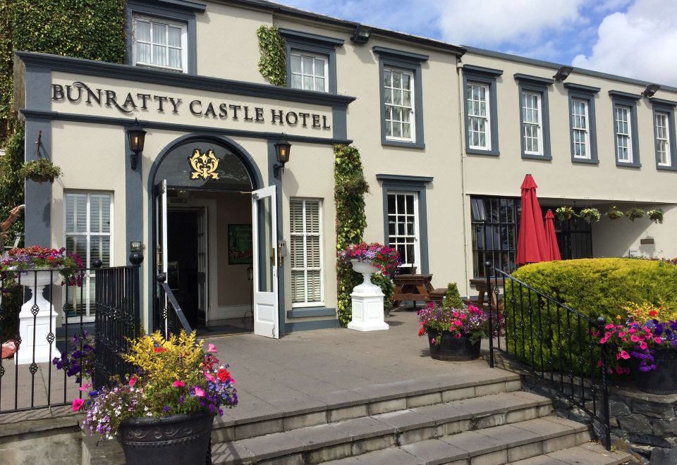 the entrance to the inratty castle hotel with steps leading up to it and a red umbrella on the right side at Bunratty Castle Hotel
