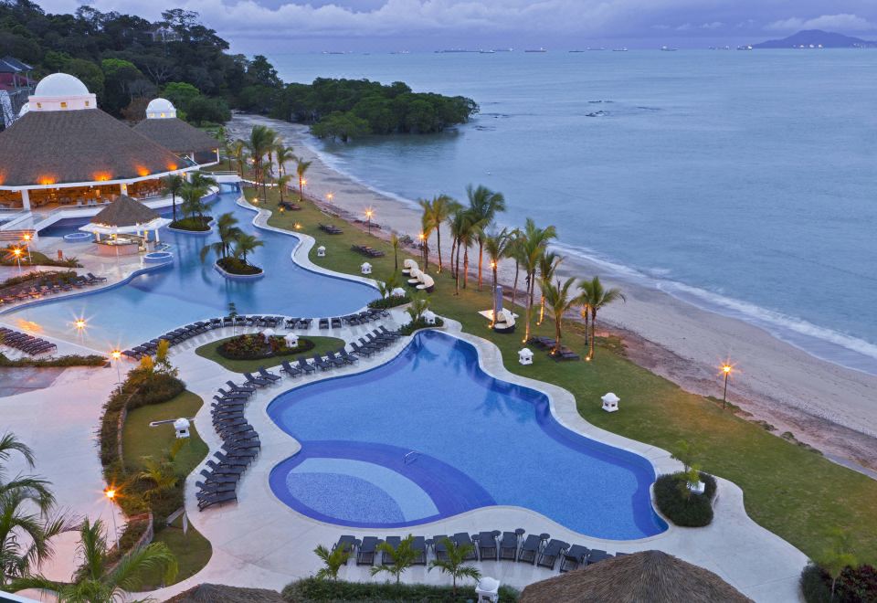 a resort with a large pool surrounded by palm trees , a beach , and a hotel at The Westin Playa Bonita Panama