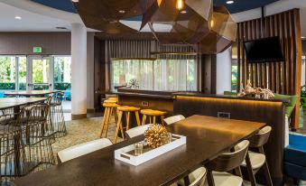 a bar area in a hotel lobby , with several chairs and tables arranged around it at SpringHill Suites Vero Beach