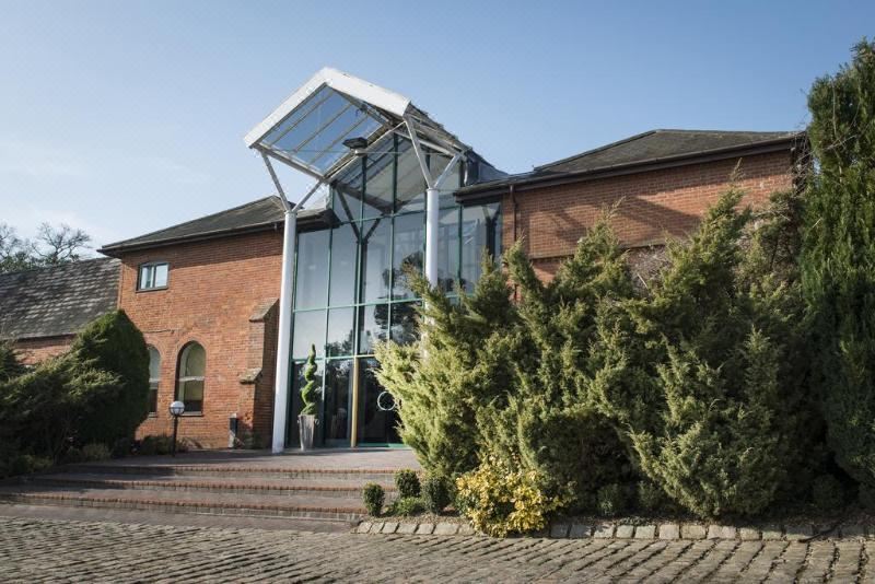 a brick building with a large glass entrance and a brick path leading up to it at De Vere Latimer Estate